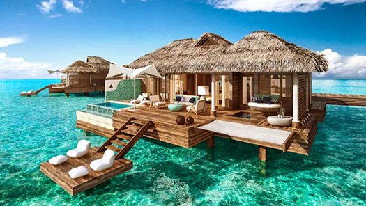 Luxury overwater bungalow with thatched roof, surrounded by turquoise waters, featuring a private deck and lounge chairs, ideal for all-inclusive family vacations and tropical getaways.