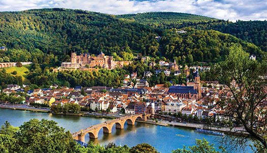Scenic view of Heidelberg, Germany, featuring the historic castle, picturesque buildings along the river, and lush green hills, highlighting unique international travel destinations.